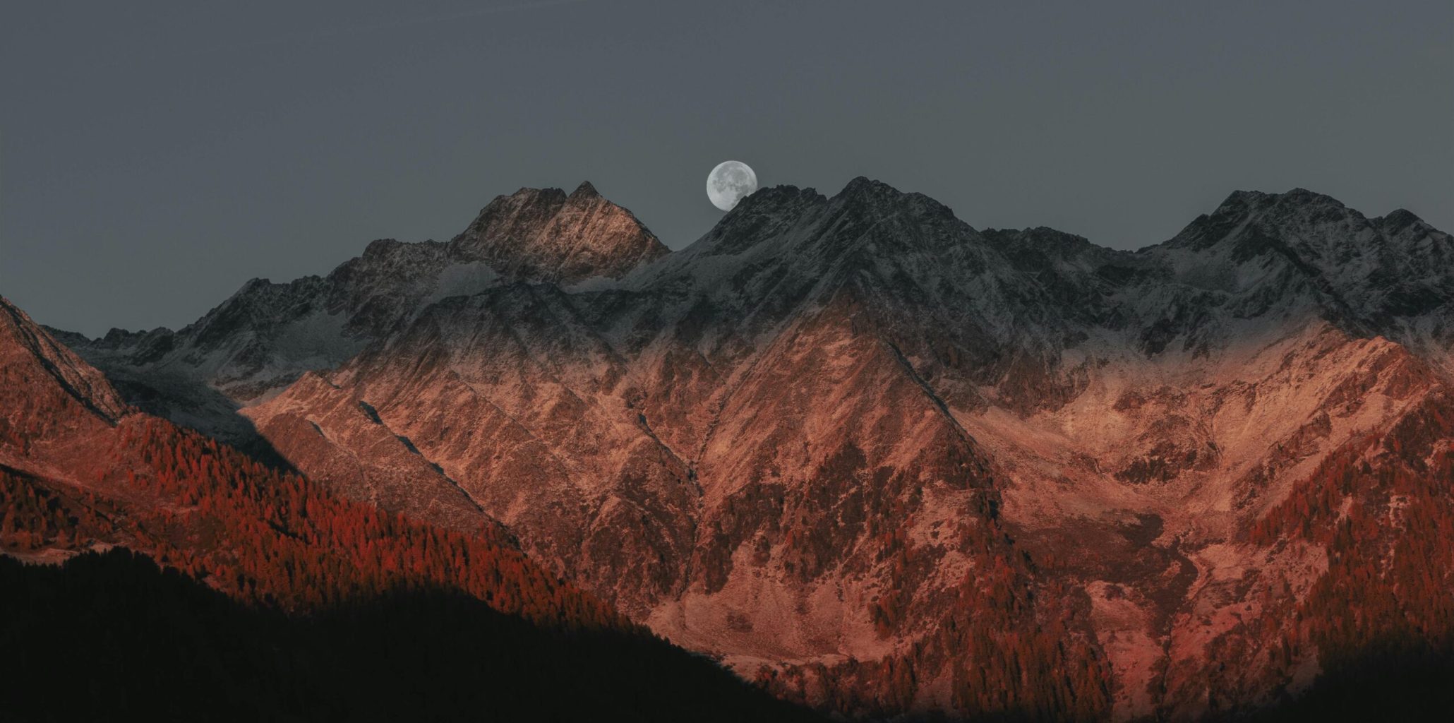 Stunning view of mountain peaks under moonlight with a twilight glow creating a dramatic landscape.