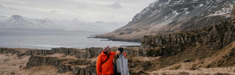 A couple embraces in a dramatic Icelandic landscape, showcasing love and adventure.