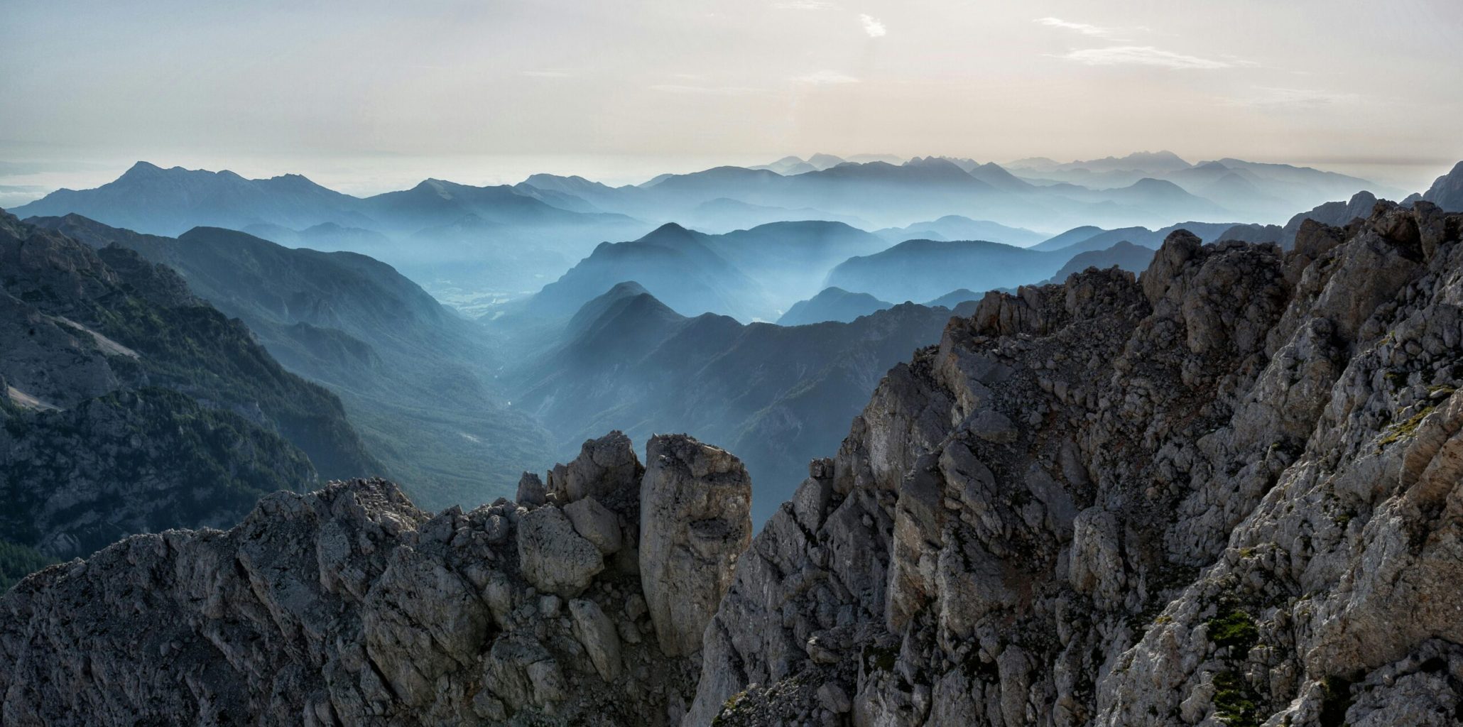 Capture of a tranquil mountain range at dawn with misty valleys and rocky peaks.