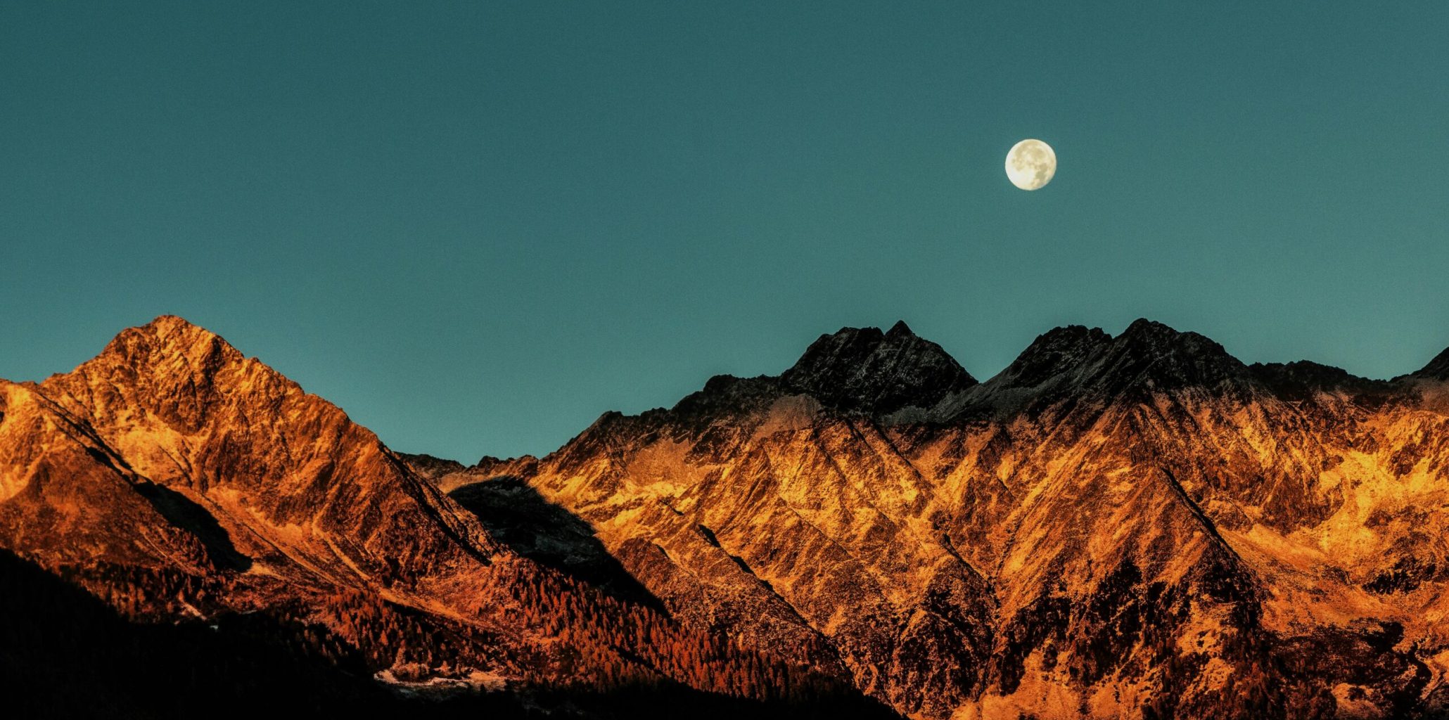 Breathtaking view of mountains with a full moon at twilight, capturing nature's beauty.